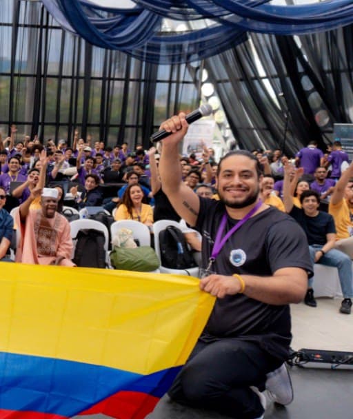 Anuar Harb, co-founder, holding a microphone and a Colombian flag in front of an event audience